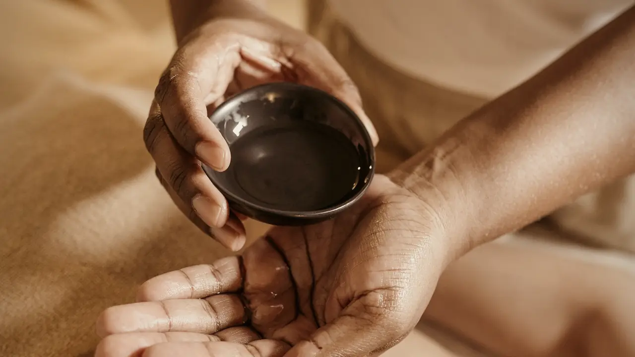 Warm oil poured from a bowl over a client's back by candlelight